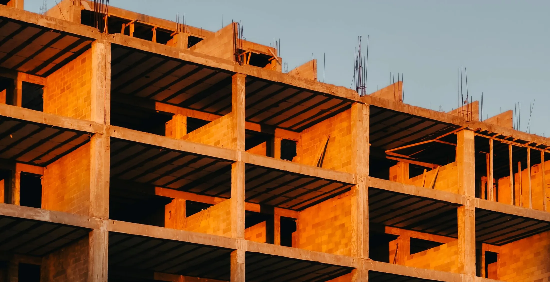 Estrutura de concreto de um edifício em construção ao entardecer, imagem ilustrativa